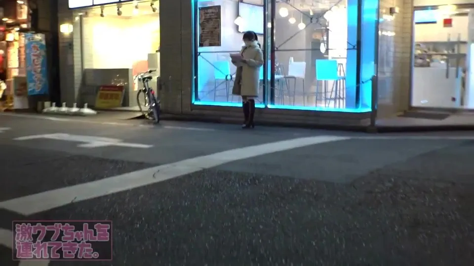 Asian woman reads in front of glowing store window