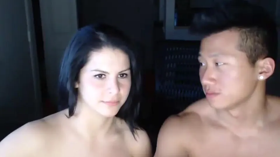 Muscular Asian guy and brunette woman in passionate bedroom scene