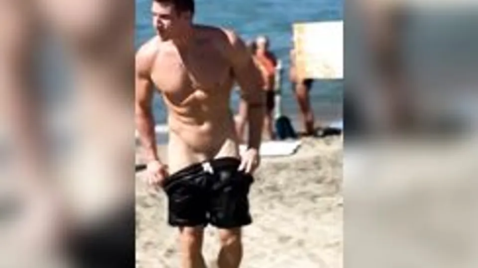Man takes off swimming trunks on a beach