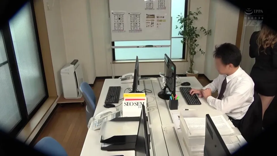 asian man types at desk with woman standing behind