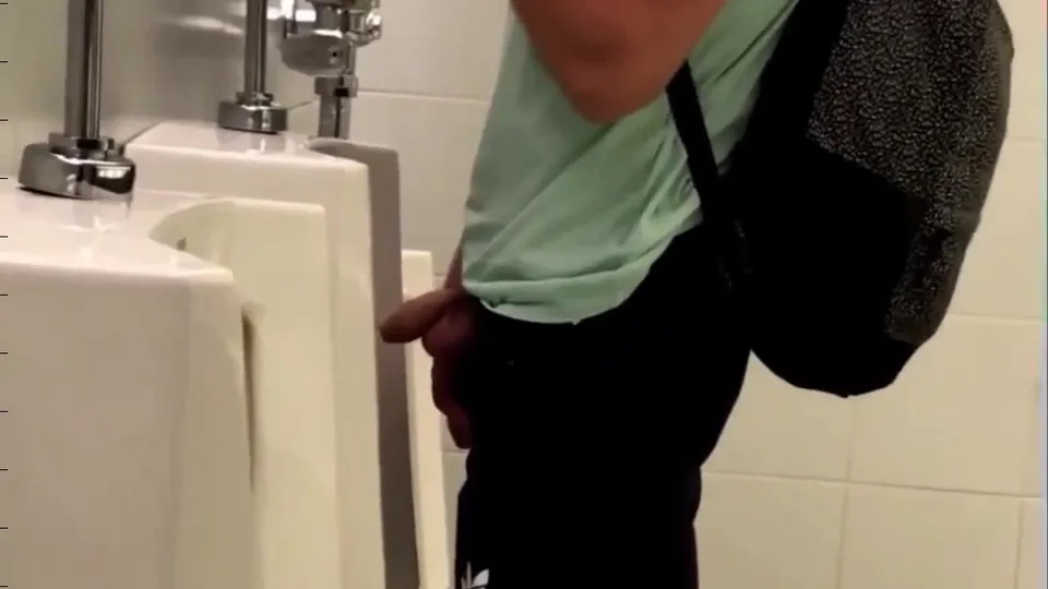 Unbeschnittener Mann pisst an Pissoir